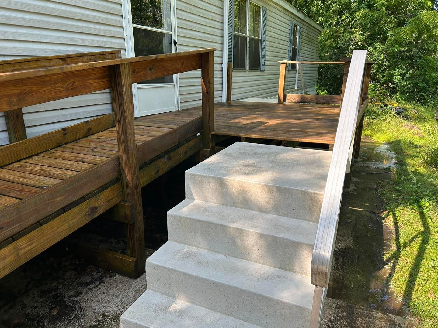 A wooden deck with concrete steps leading up to it.