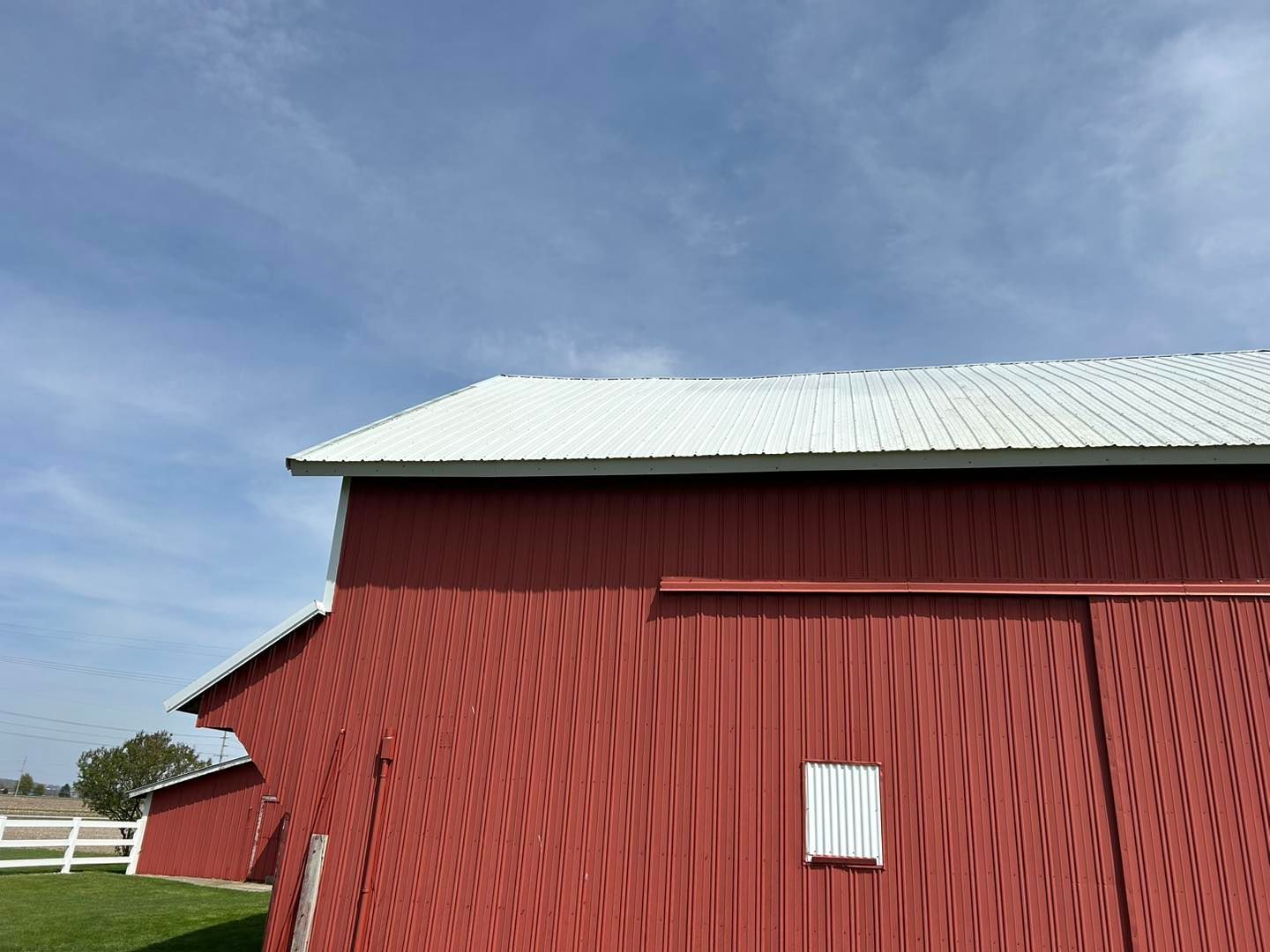 A red barn with a white roof and a white fence in the background.