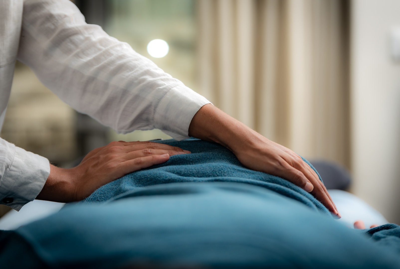 A person is laying on a bed getting a massage from a doctor.