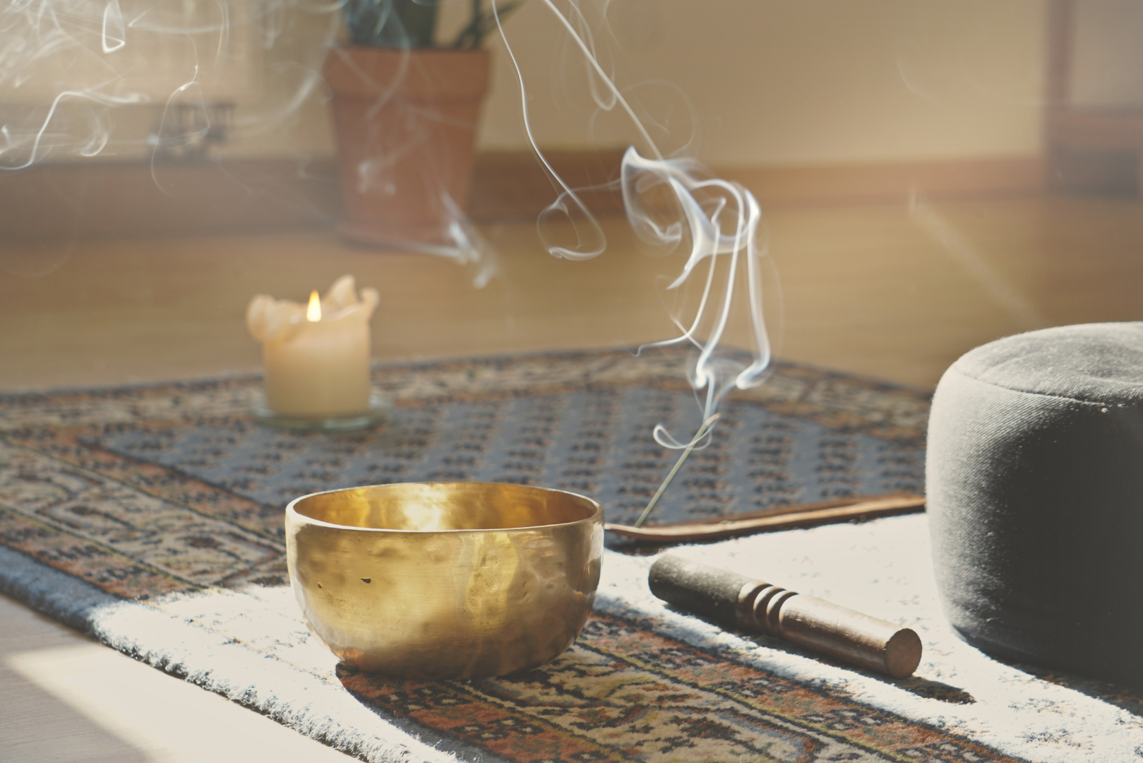 A bowl of incense is sitting on a rug next to a candle.