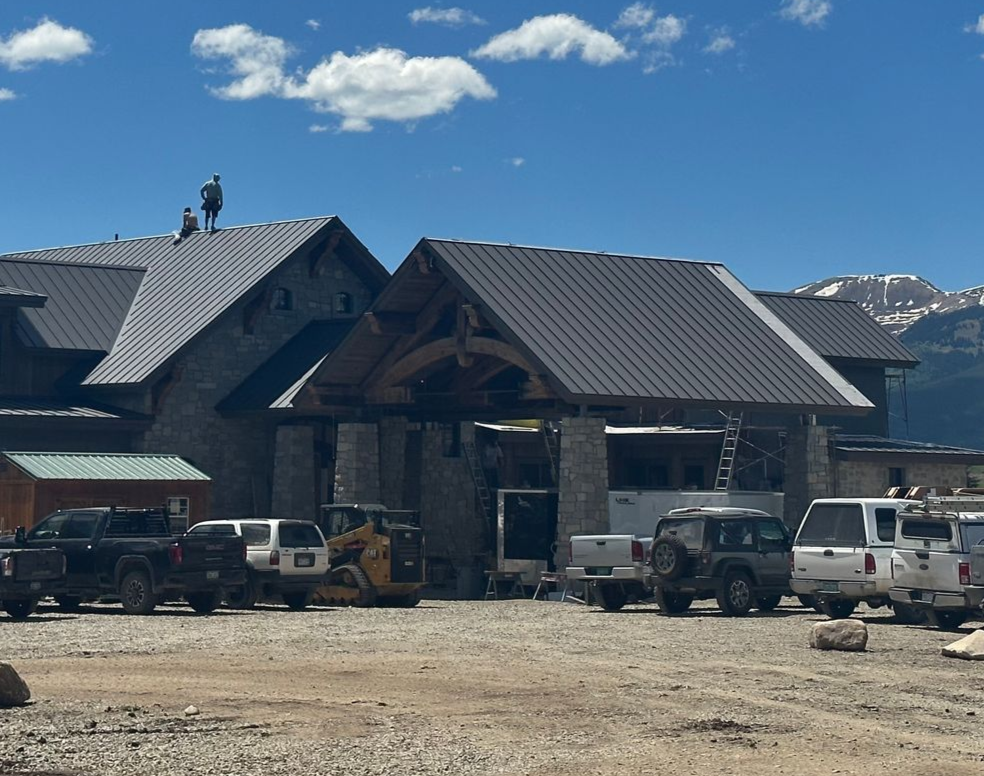 A group of people are working on the roof of a wooden house.