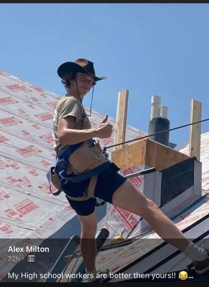 A group of people are working on the roof of a wooden house.
