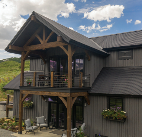 A gray house with a black roof and a balcony