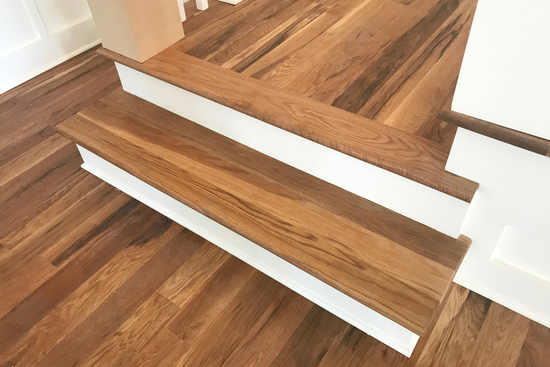 A close up of a wooden staircase with white trim