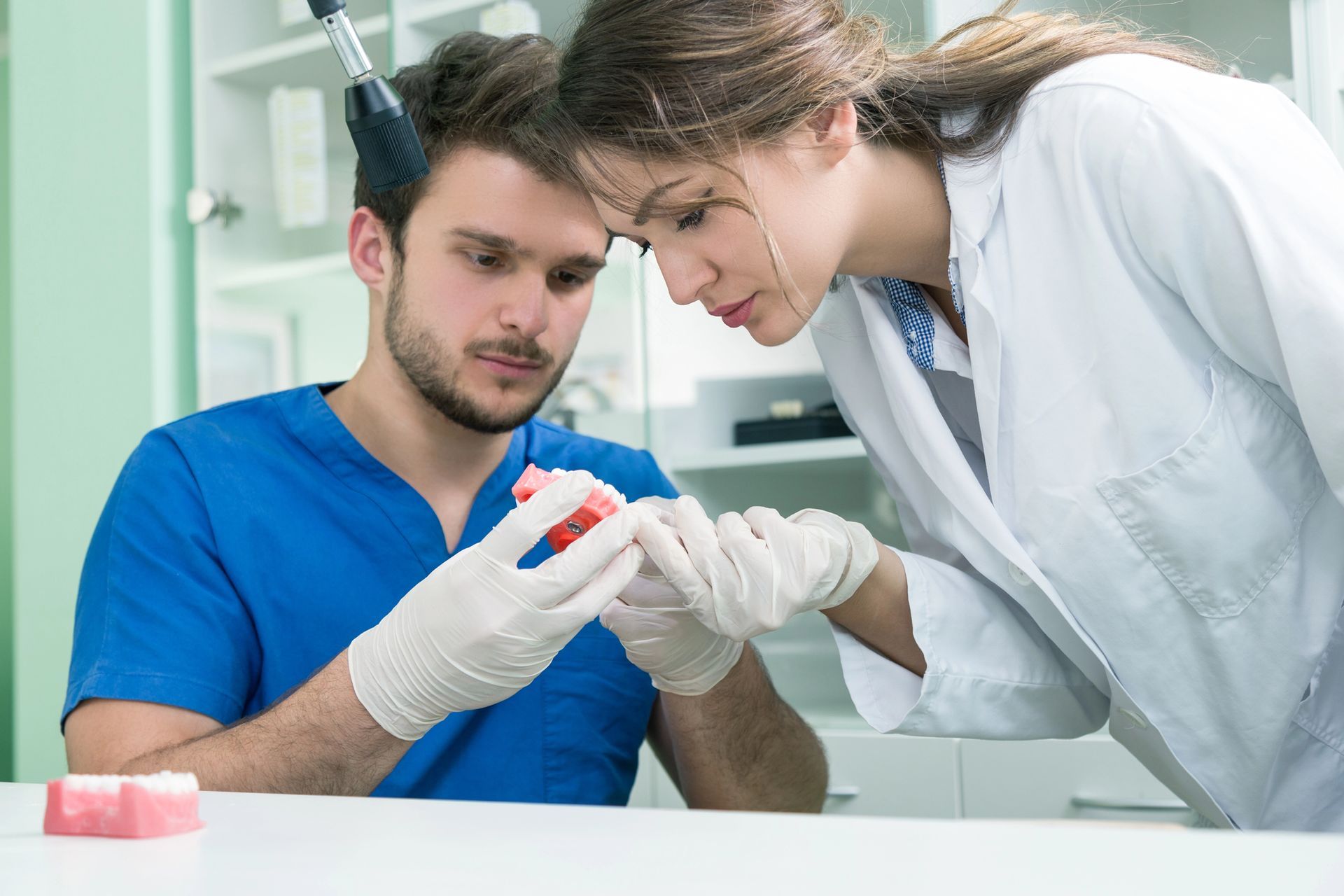 Dentista y paciente examinando un molde dental en una clínica luminosa.