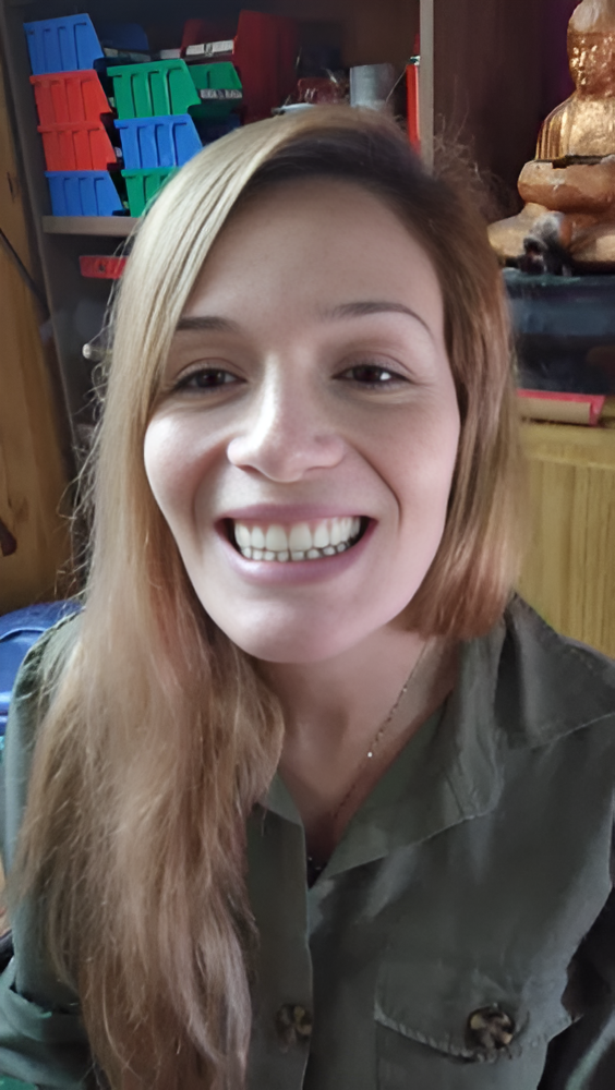 Una persona sonriente con una camisa verde oliva en el interior de un edificio