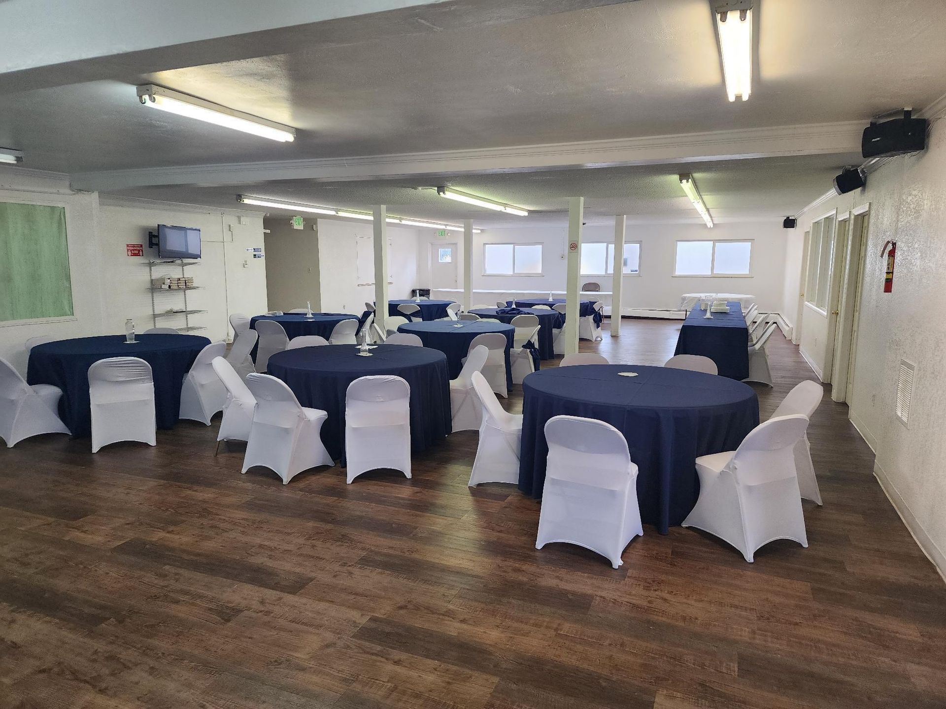 Event space with round tables covered in navy blue linens and white chair covers.