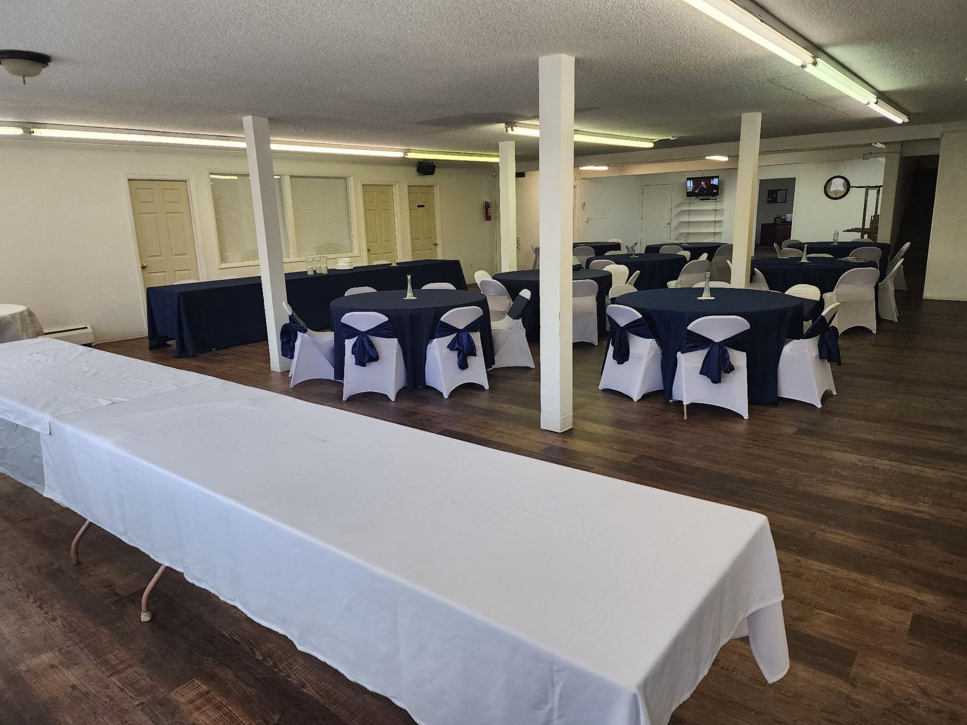 Empty event space with white and navy blue table settings.