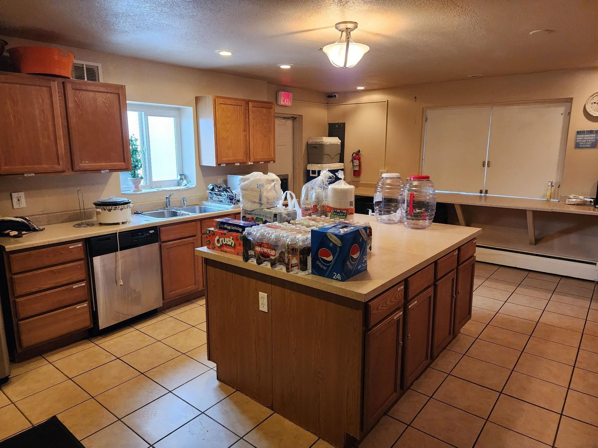Kitchen with island, cabinets, appliances, and a table in a community setting.