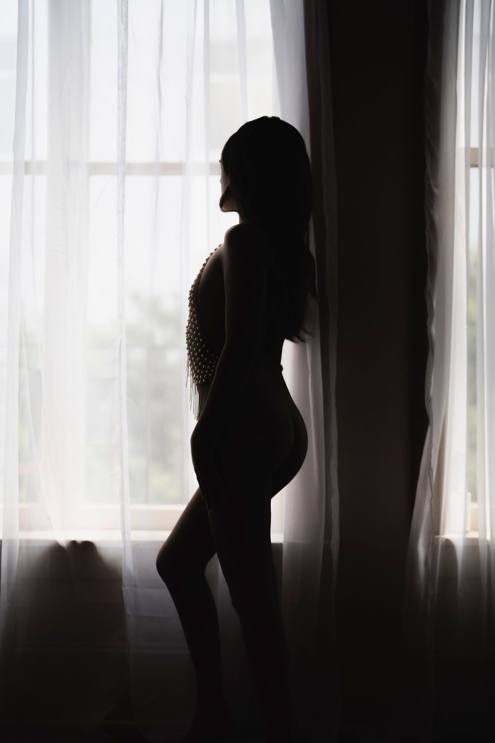 A silhouette of a woman standing in front of a window.