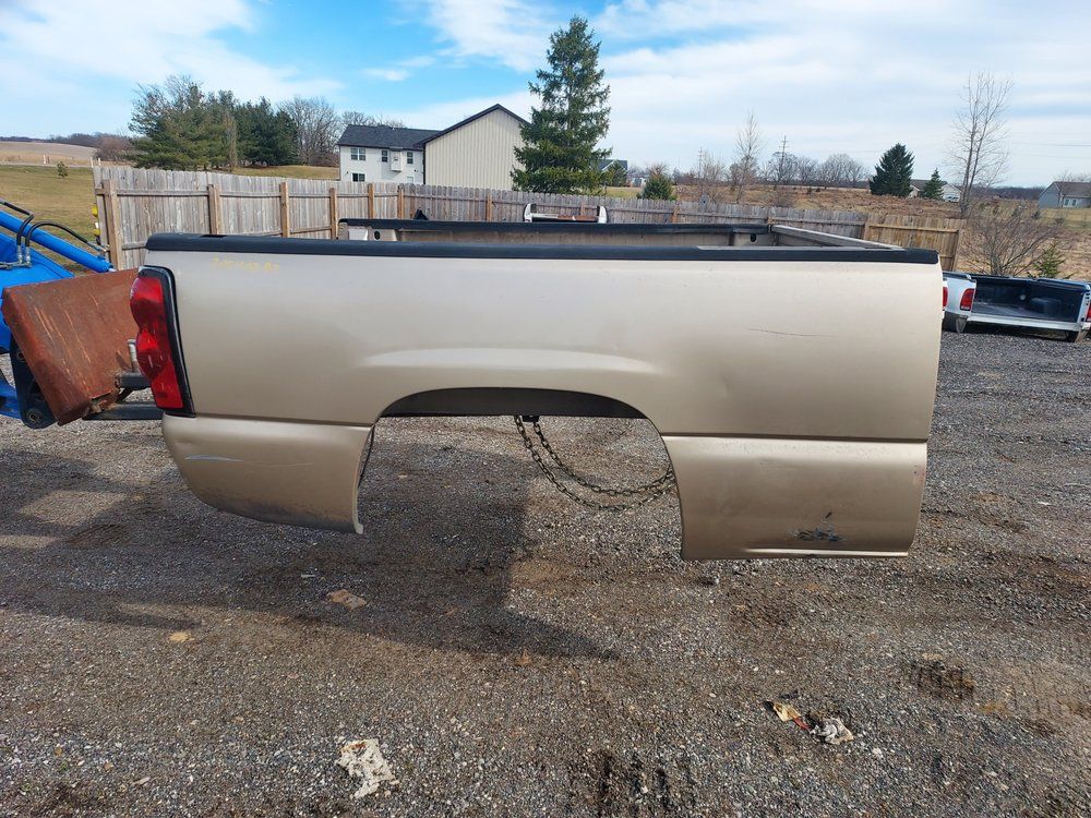 A truck bed is sitting in the dirt in a parking lot.