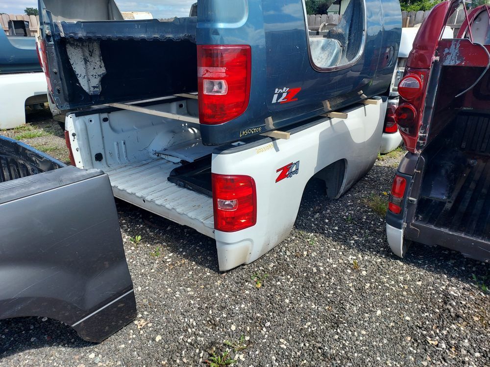 A group of pickup trucks are parked in a gravel lot.