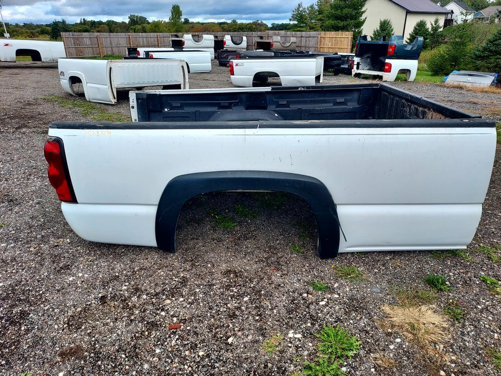 A white truck bed is sitting on top of a gravel lot.