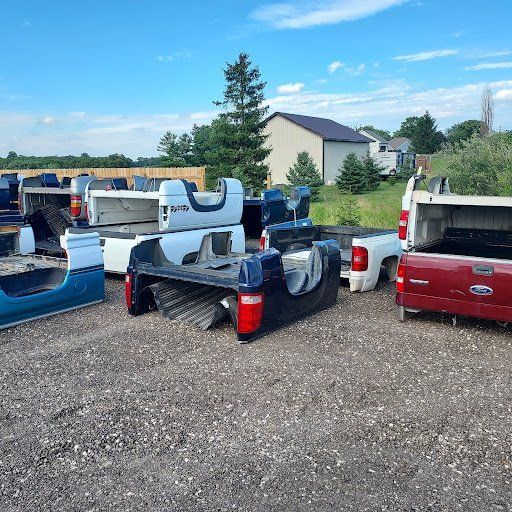 A bunch of pickup trucks are parked in a gravel lot.