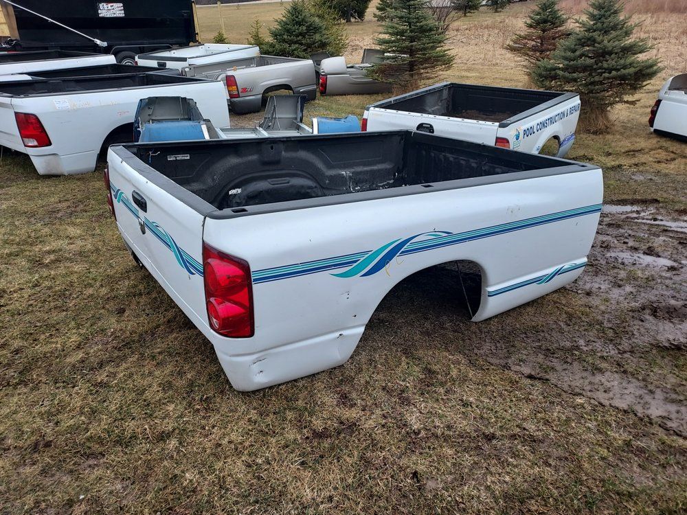 A white truck bed is sitting on top of a grass covered field.