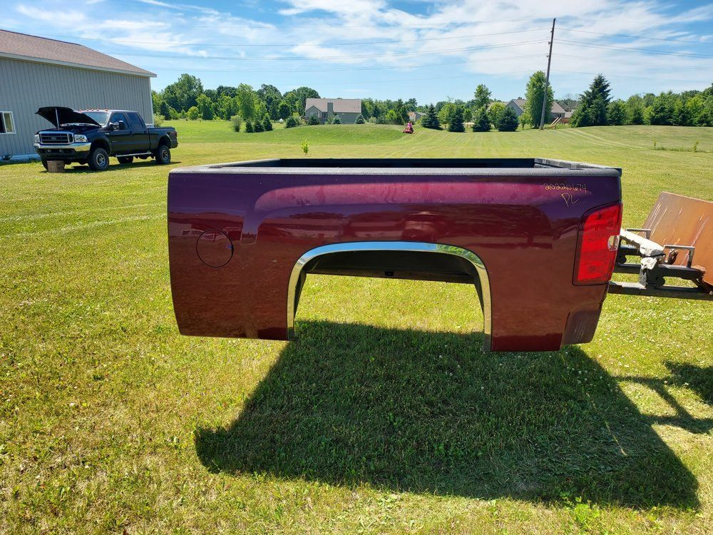 A red truck bed is sitting on top of a lush green field.