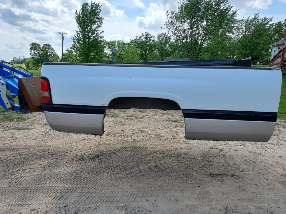A white truck bed is sitting on top of a dirt field.