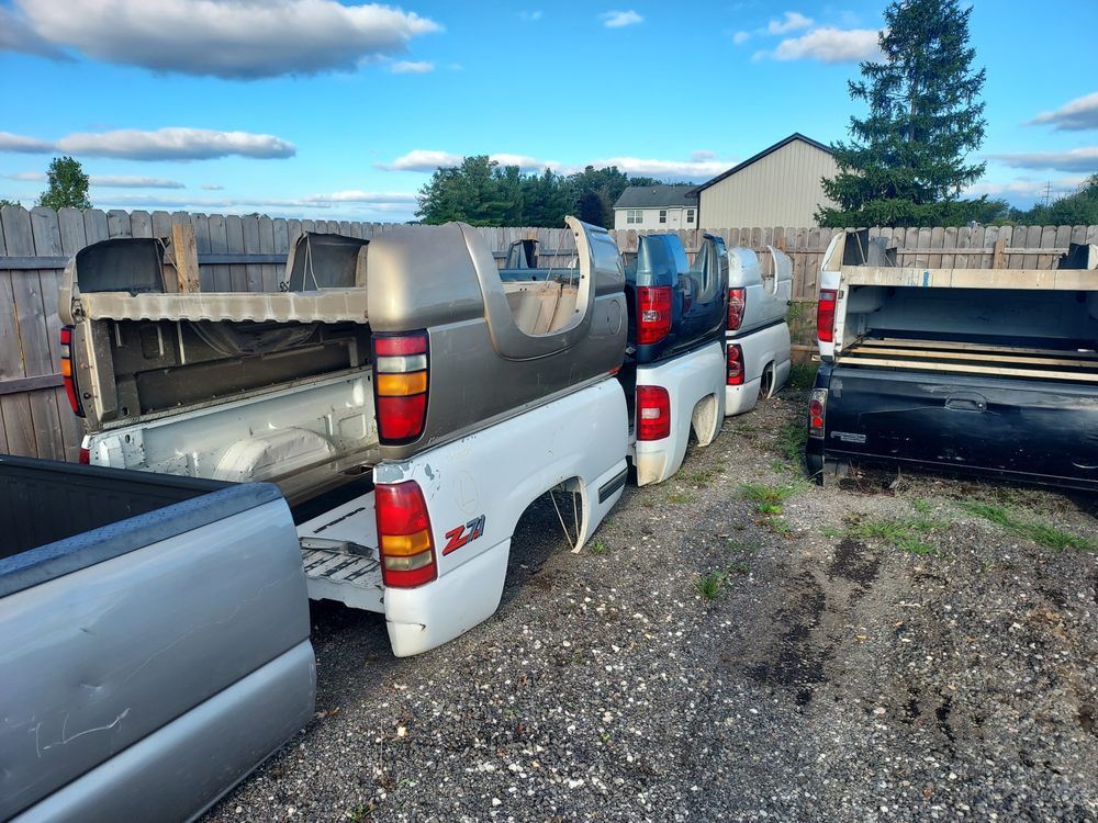 A row of pickup trucks are parked in a gravel lot