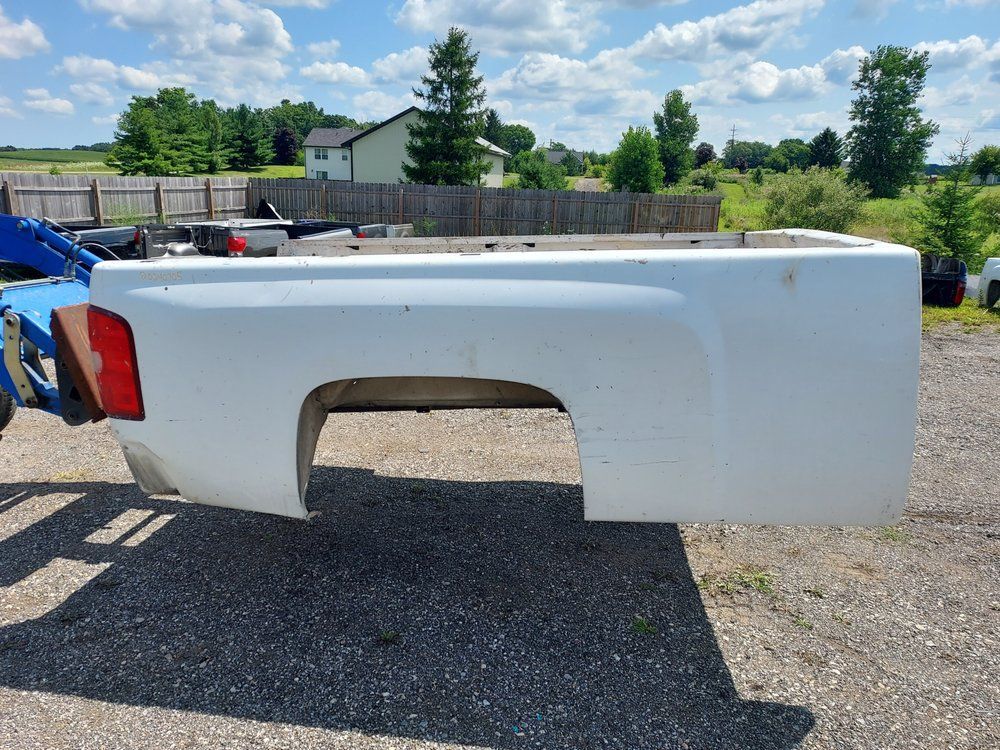 A white truck bed is sitting on top of a gravel road.