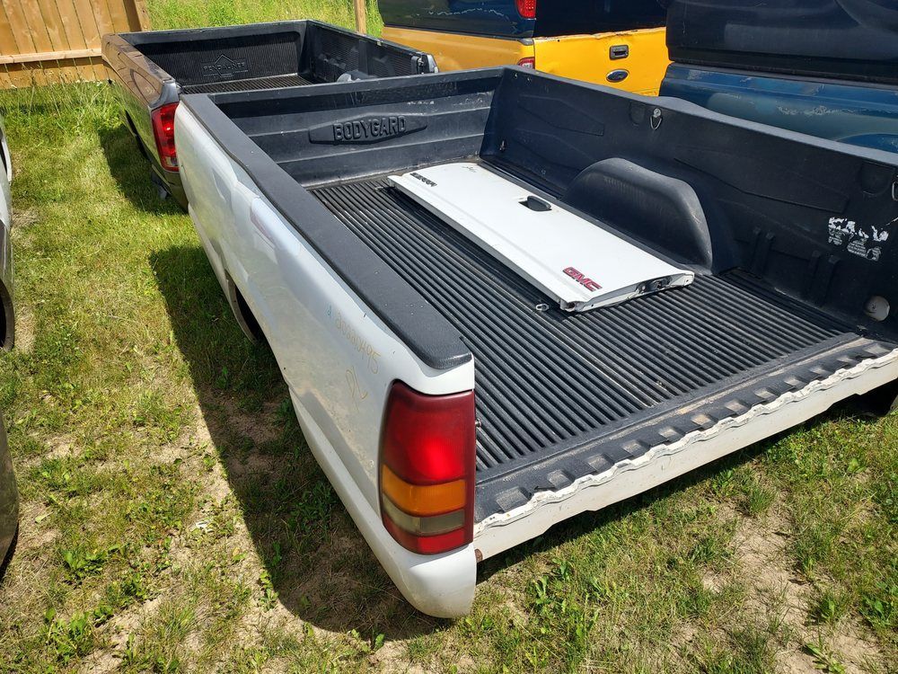 A white truck with a black bed is parked in the grass.