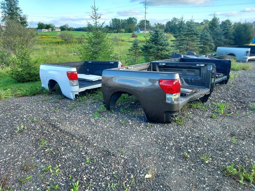 A row of pickup trucks are parked in a gravel lot.