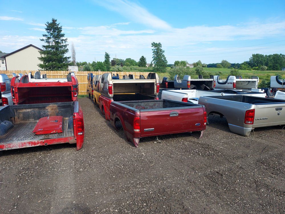 A row of pickup trucks are parked in a gravel lot