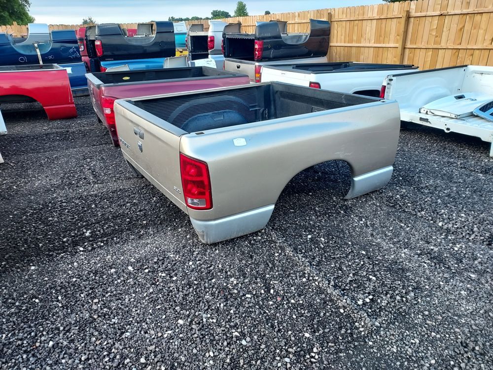 A row of pickup trucks are parked in a gravel lot.