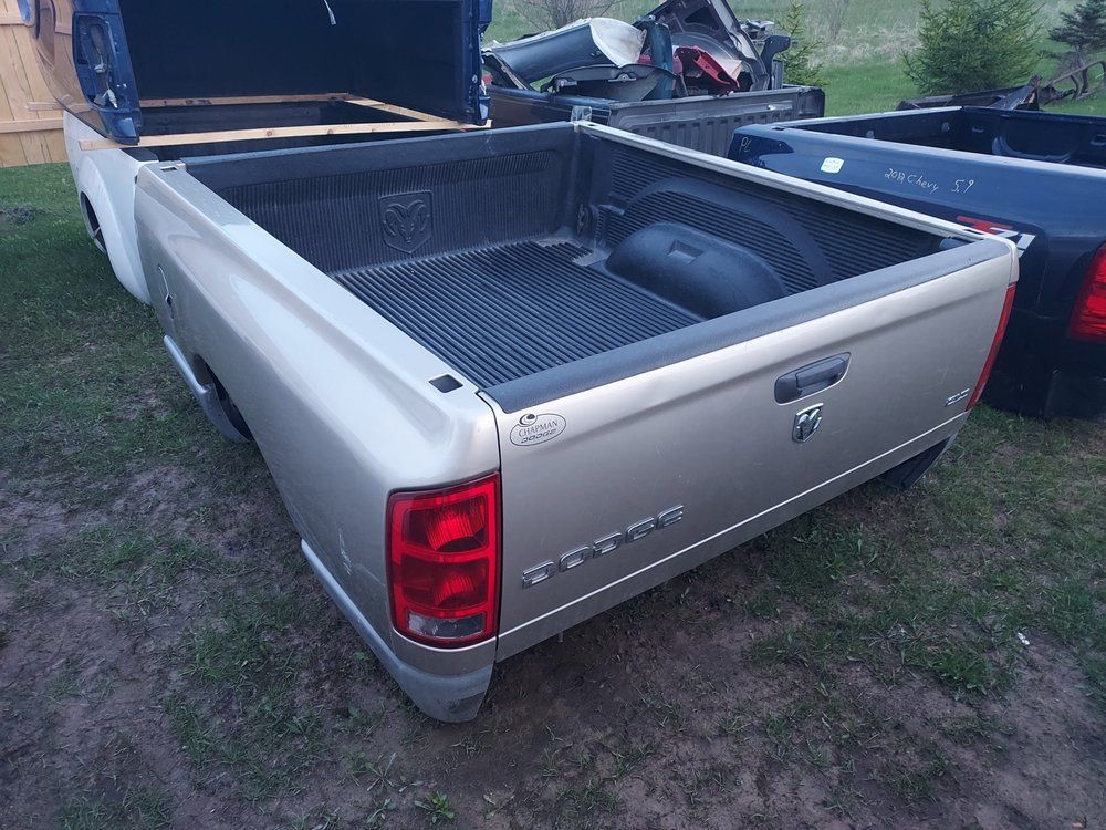 A silver dodge ram truck is parked in a grassy field.