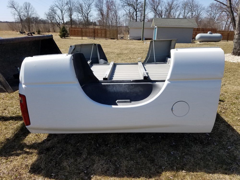A white truck bed is sitting in a grassy field
