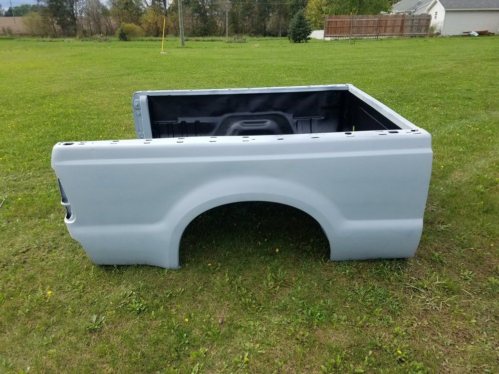 A white truck bed is sitting on top of a lush green field.