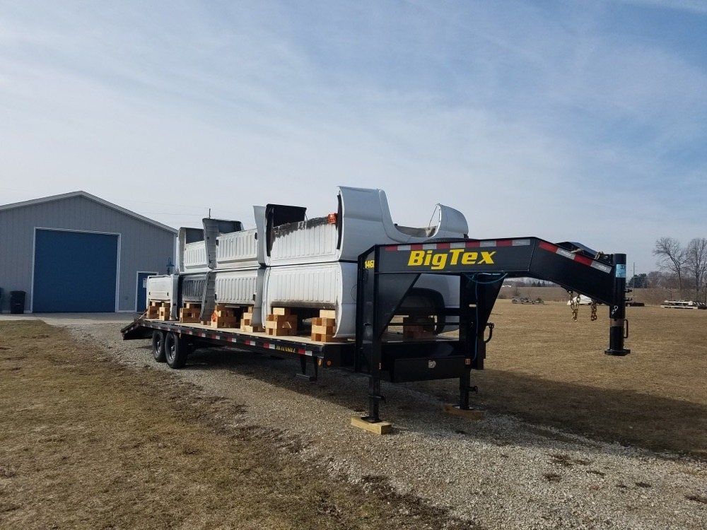 A big tex trailer is parked on the side of a dirt road.