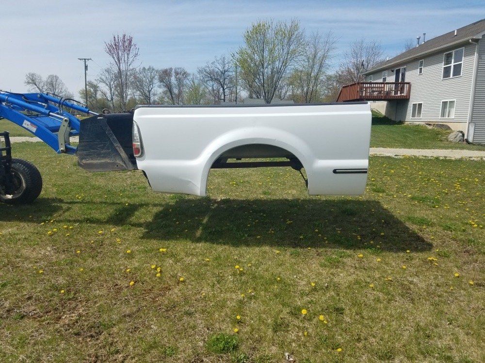 A white truck bed is sitting on top of a lush green field.