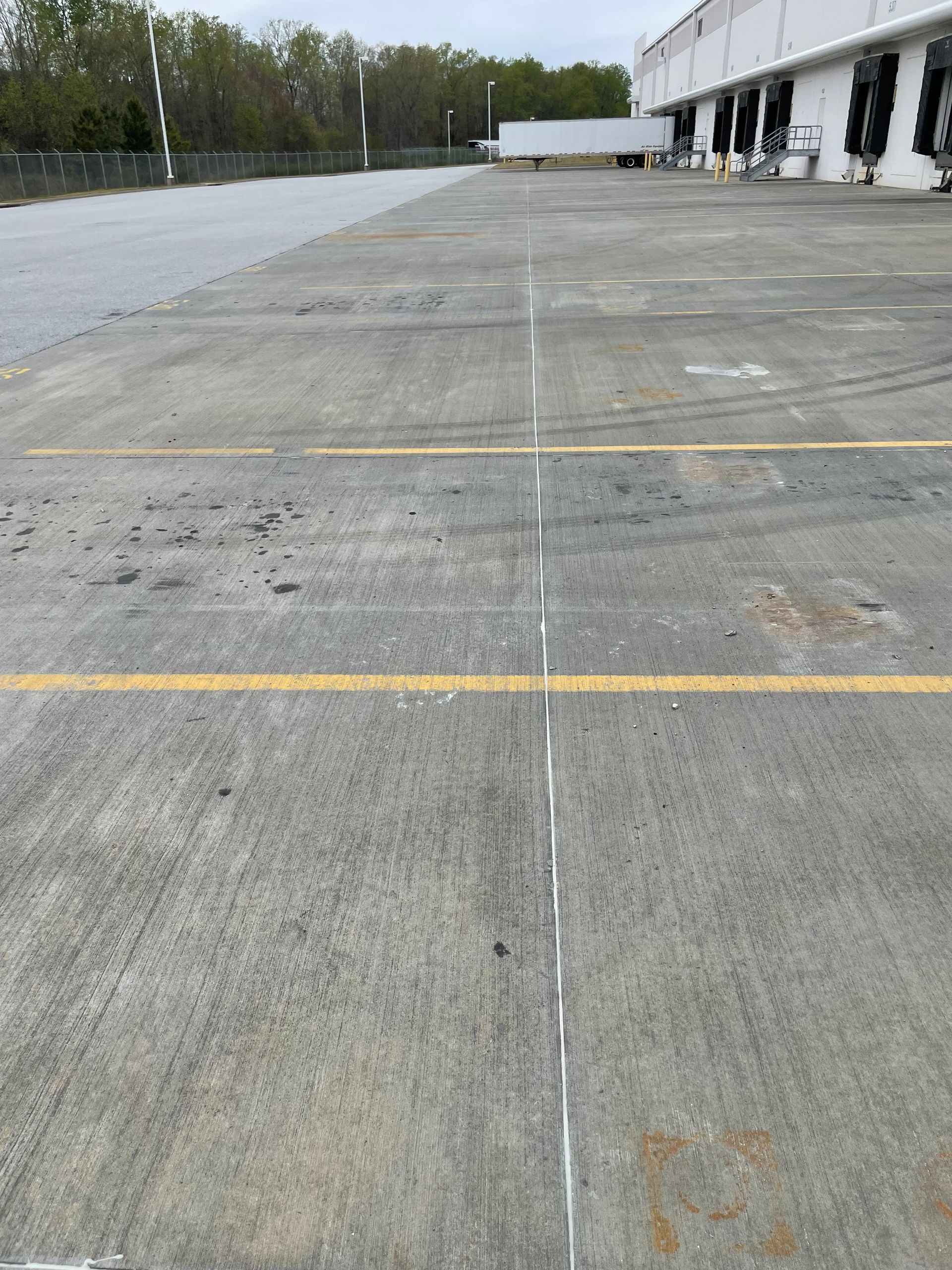 A concrete parking lot with a yellow line in the middle.
