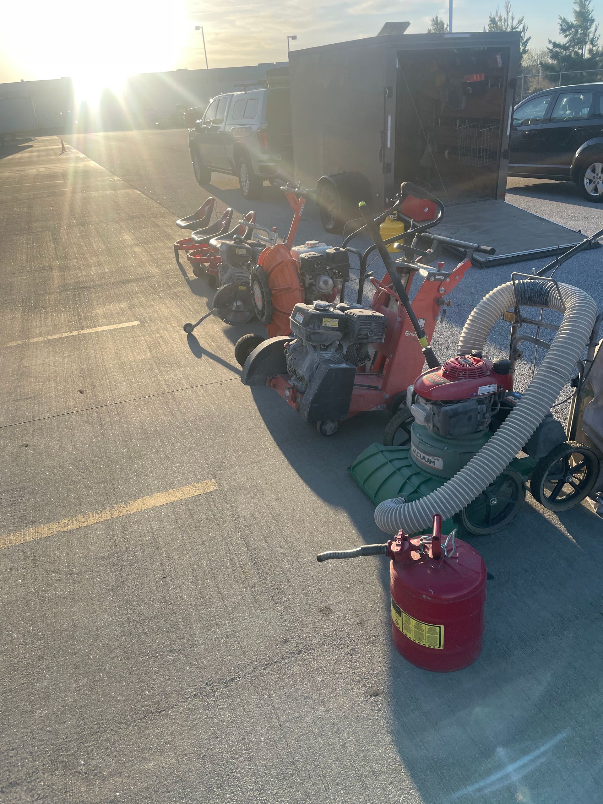 A row of lawn mowers are parked in a parking lot.