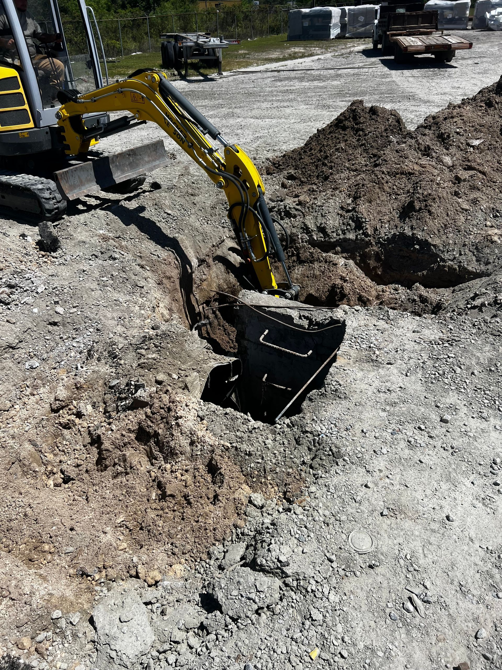 A yellow excavator is digging a hole in the ground.