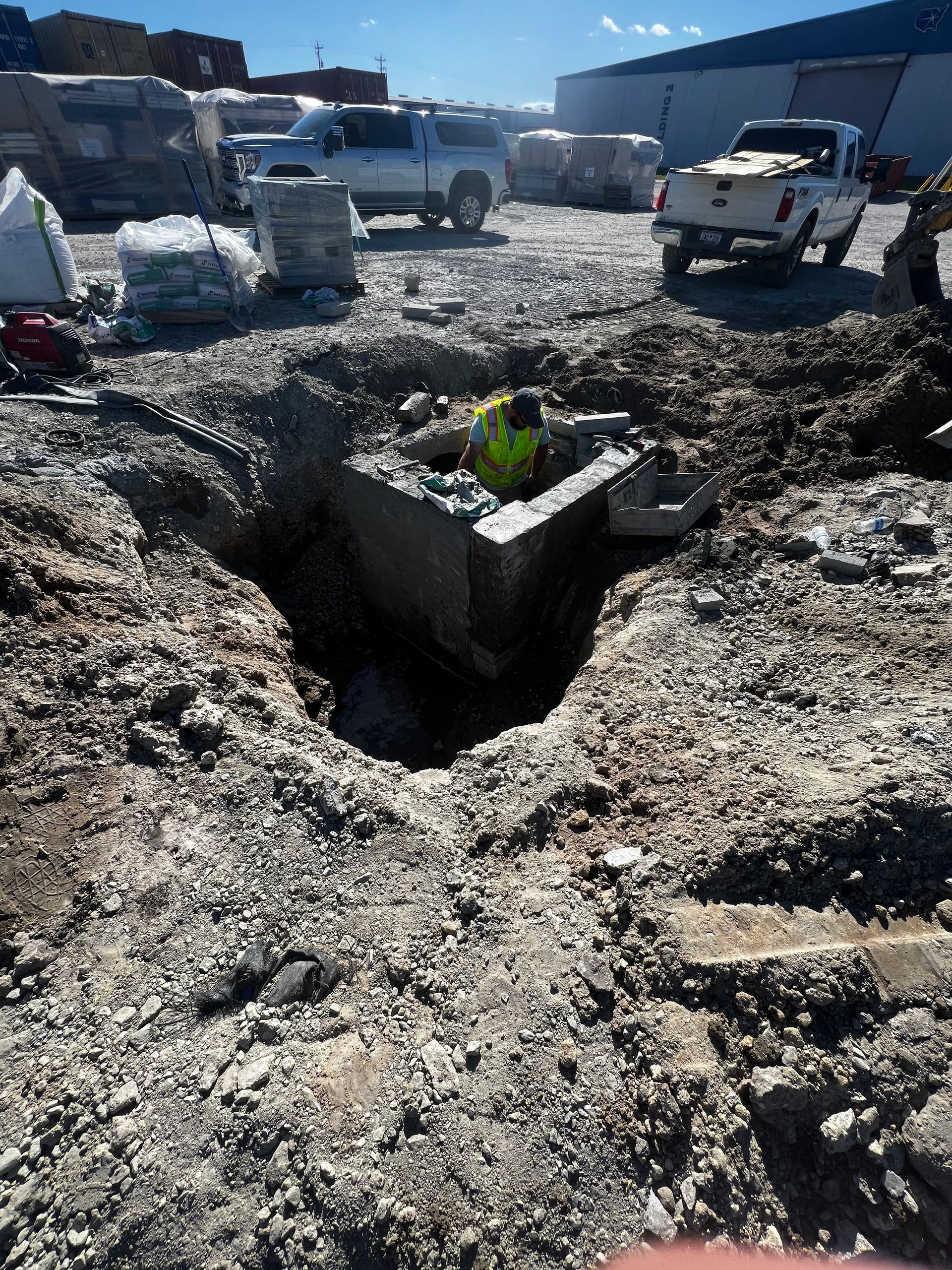 A man in a yellow vest is digging a hole in the ground.