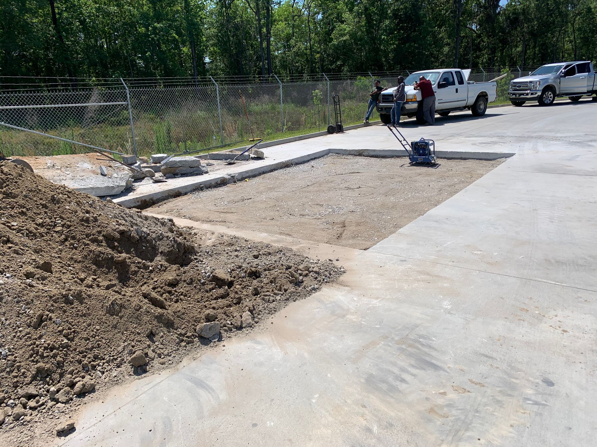 A white truck is parked in a parking lot next to a pile of dirt.