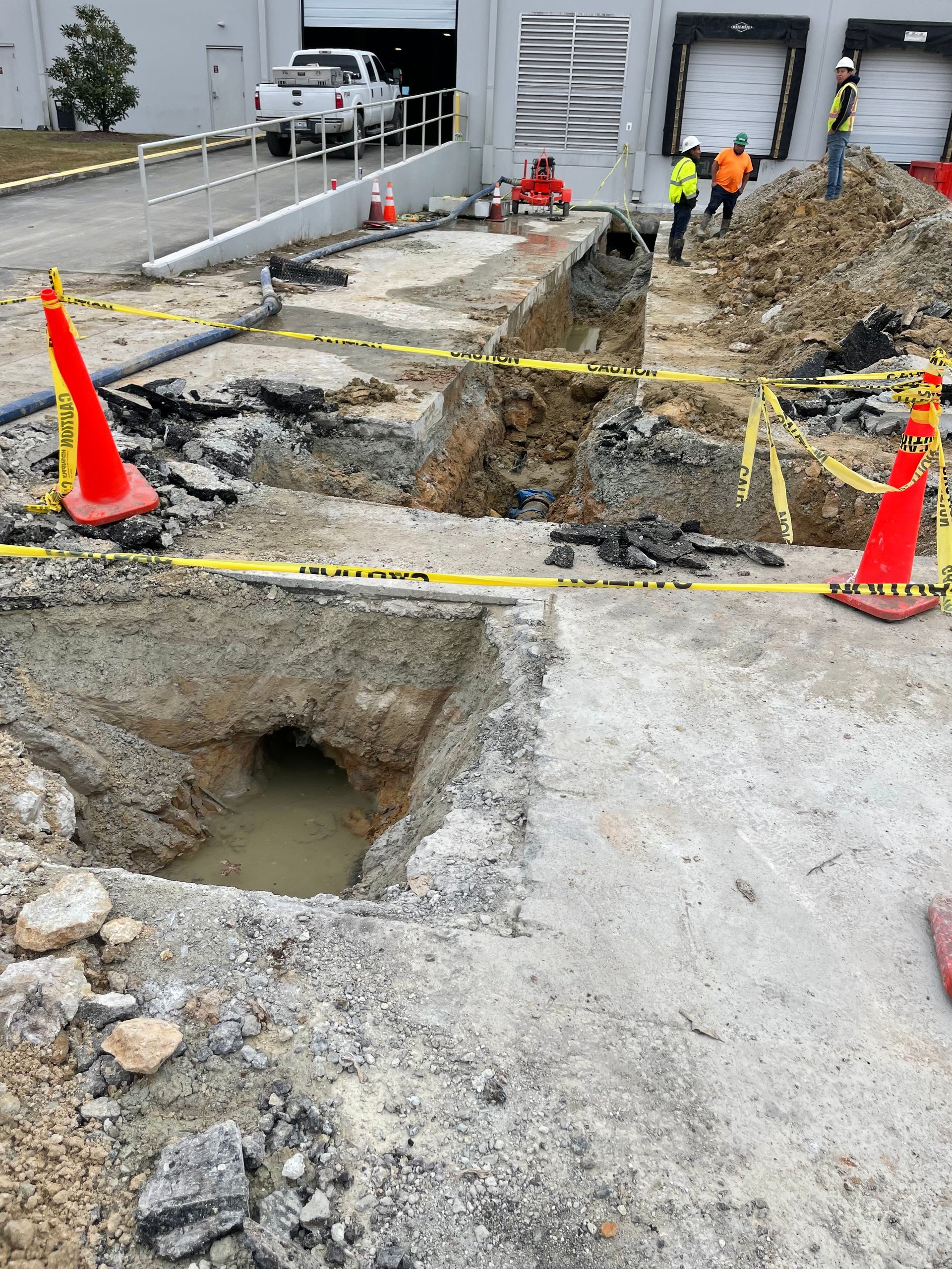 A group of construction workers are working on a hole in the ground.