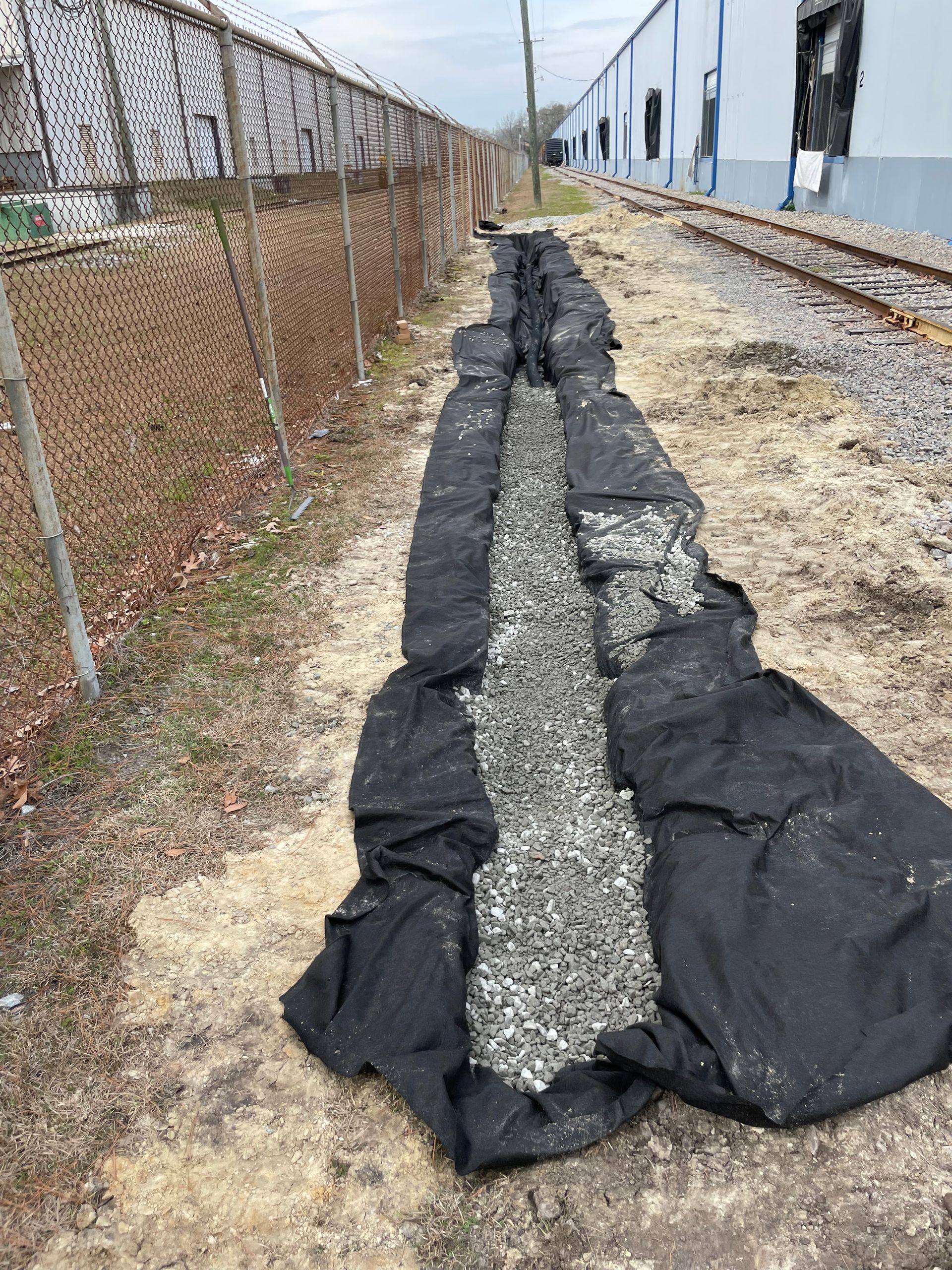 A pile of gravel is sitting in the dirt next to a train track.