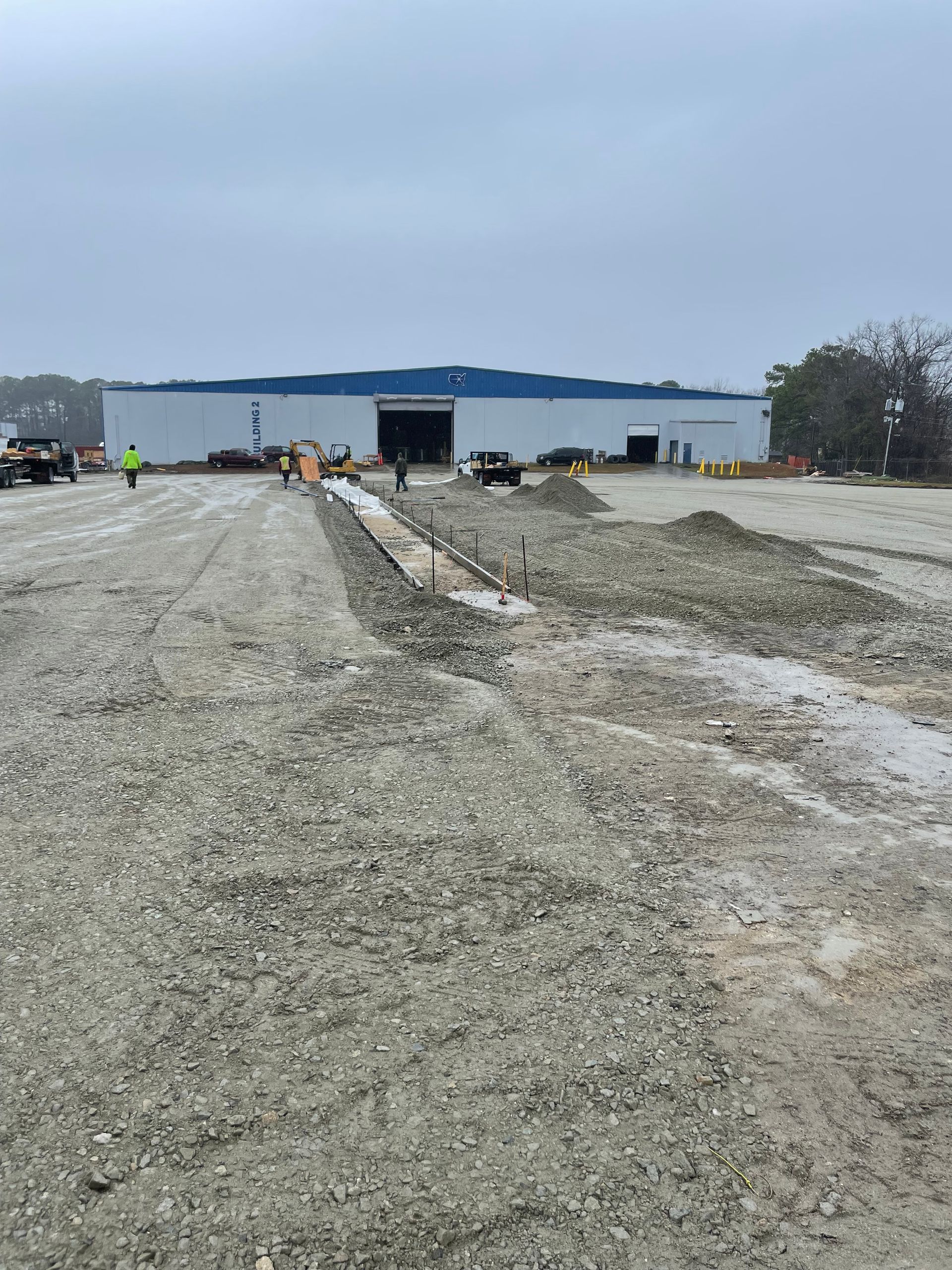 A large white building is sitting on top of a dirt field.