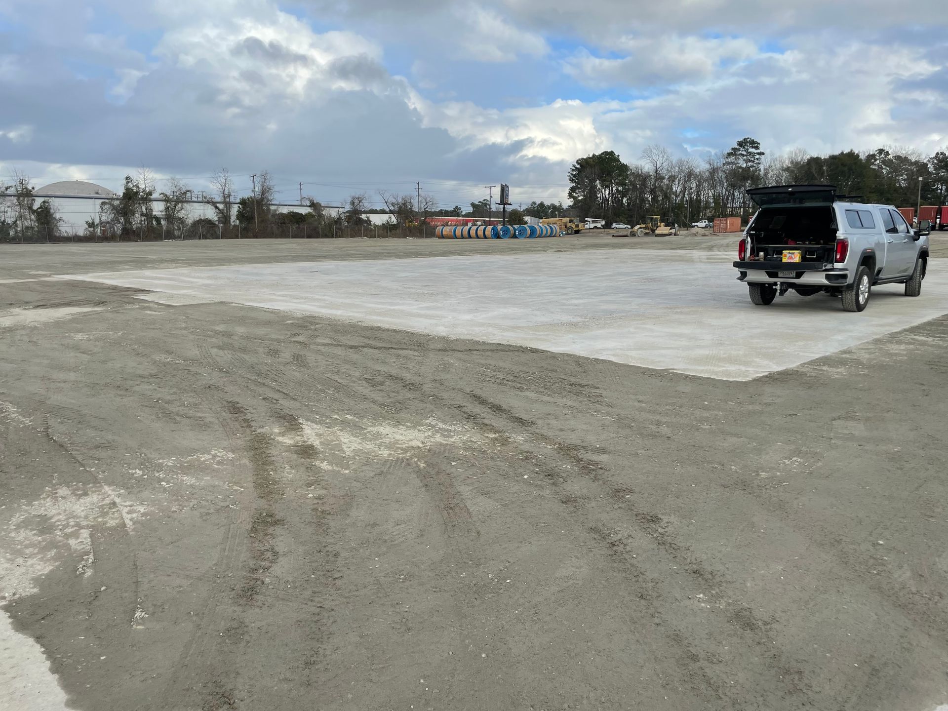 A truck is parked in a dirt lot with the trunk open