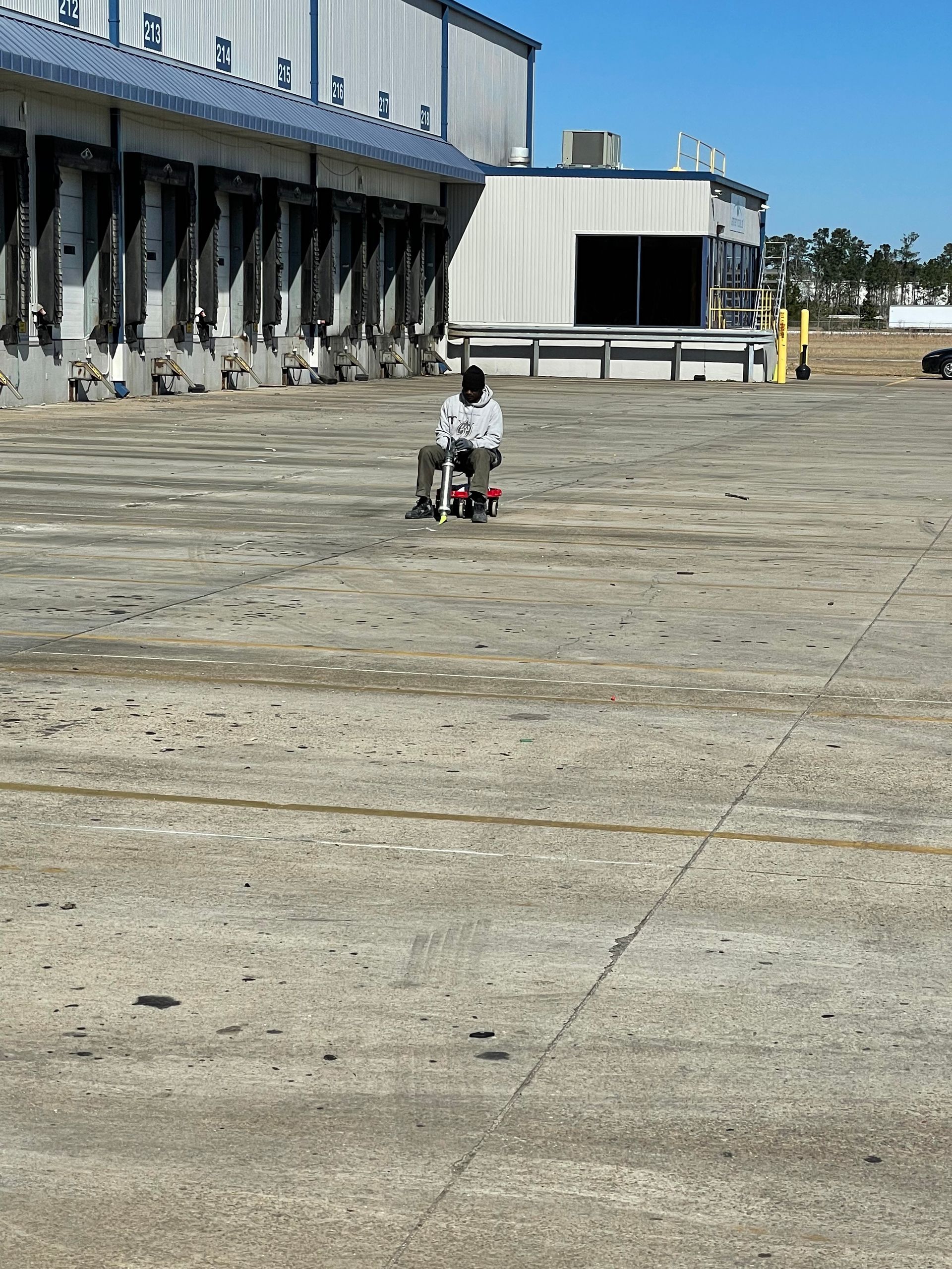 A man sits in a wheelchair in front of a warehouse