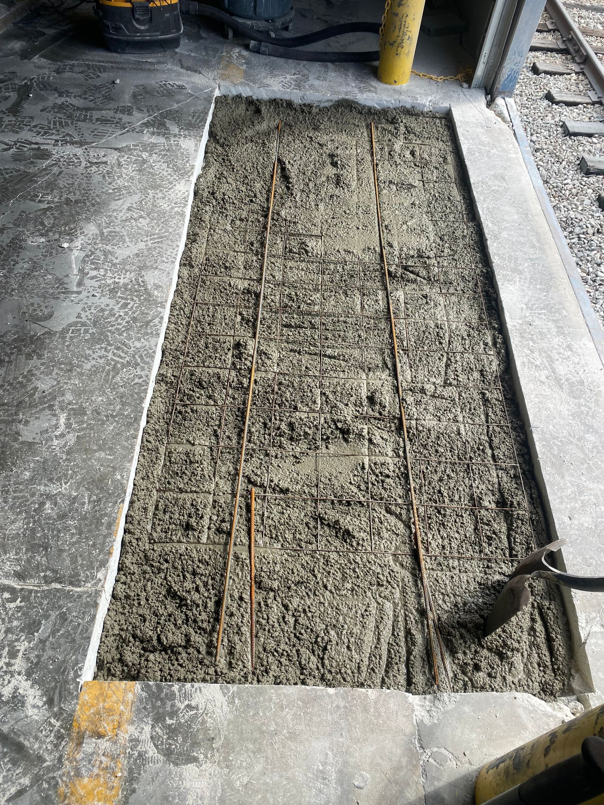 A person is pouring concrete into a hole in the ground.