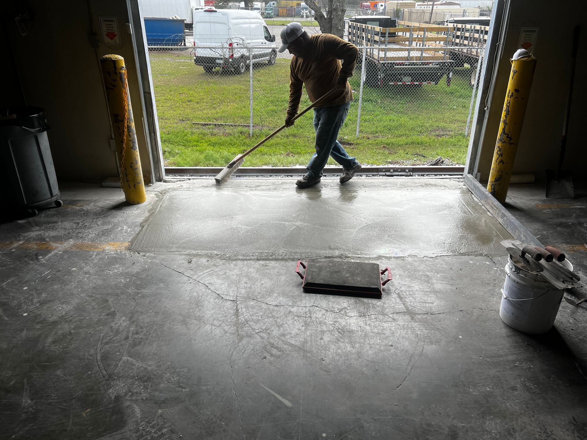 A man is sweeping the floor of a garage with a broom.