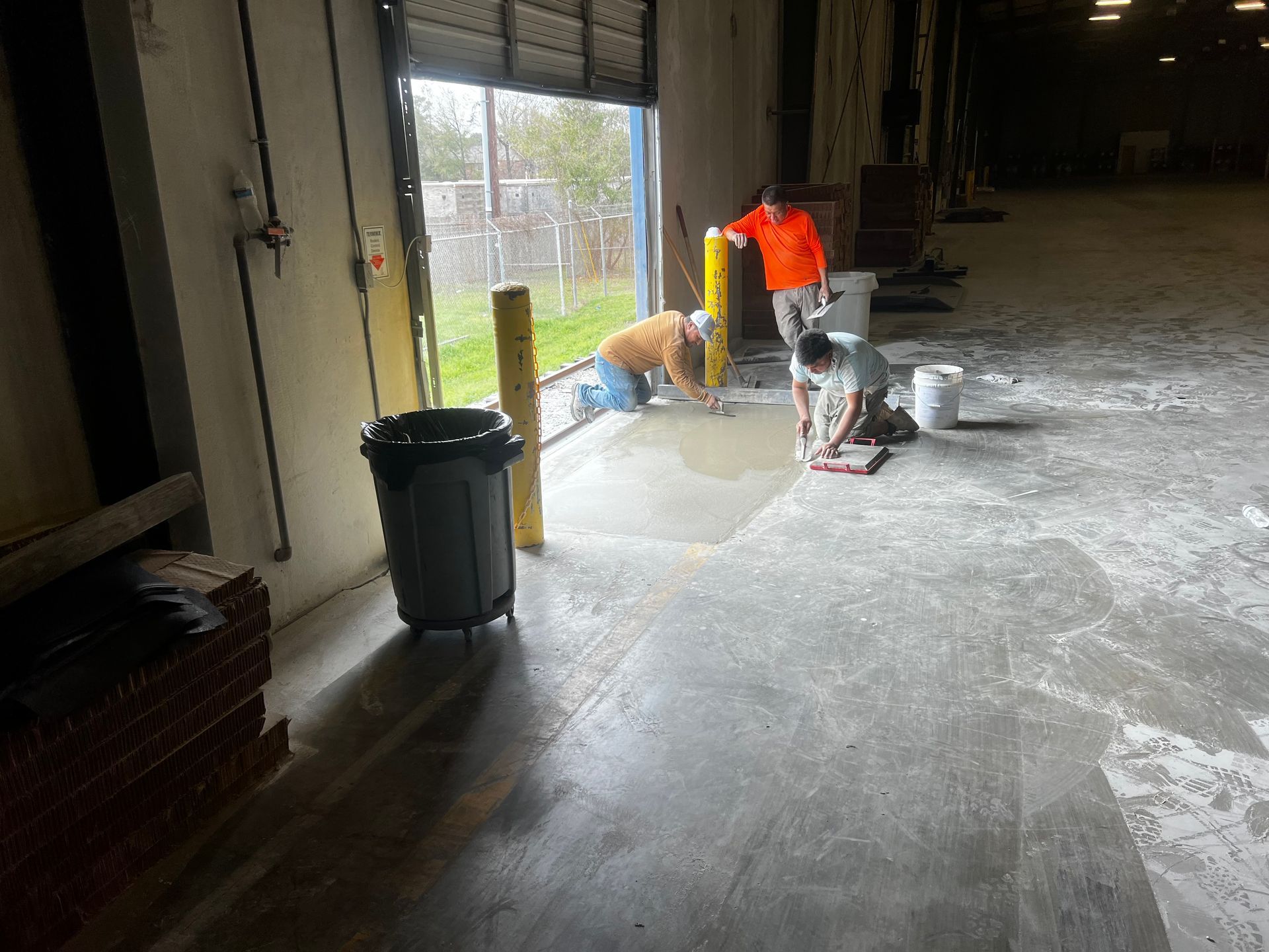 A group of men are working on the floor of a warehouse.