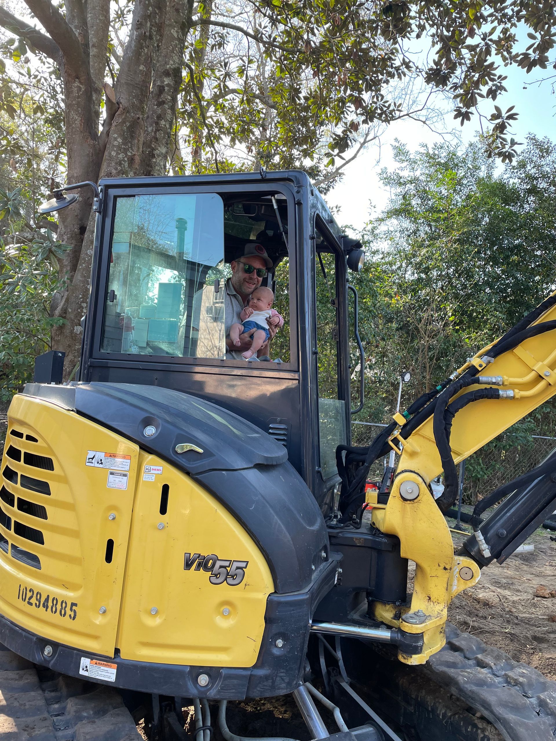 A man is sitting in the driver 's seat of a yellow excavator.