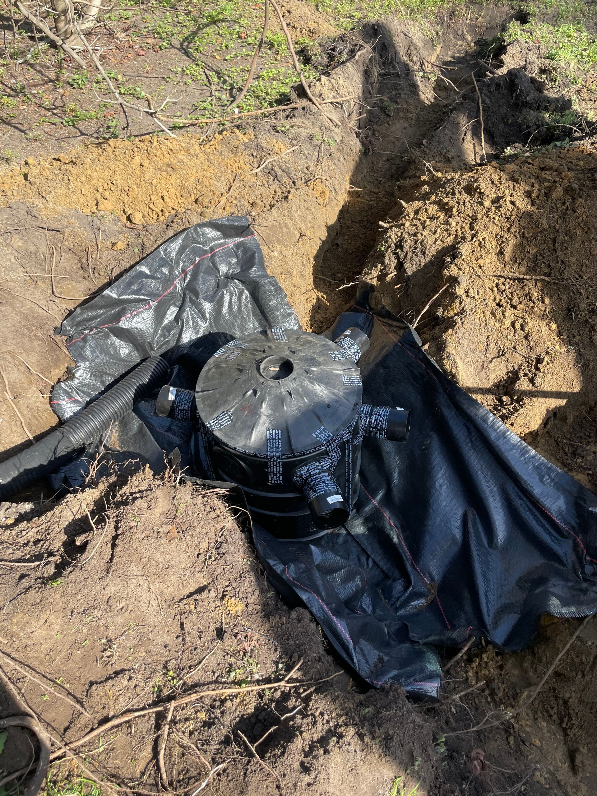 A black bag is sitting on top of a pile of dirt.