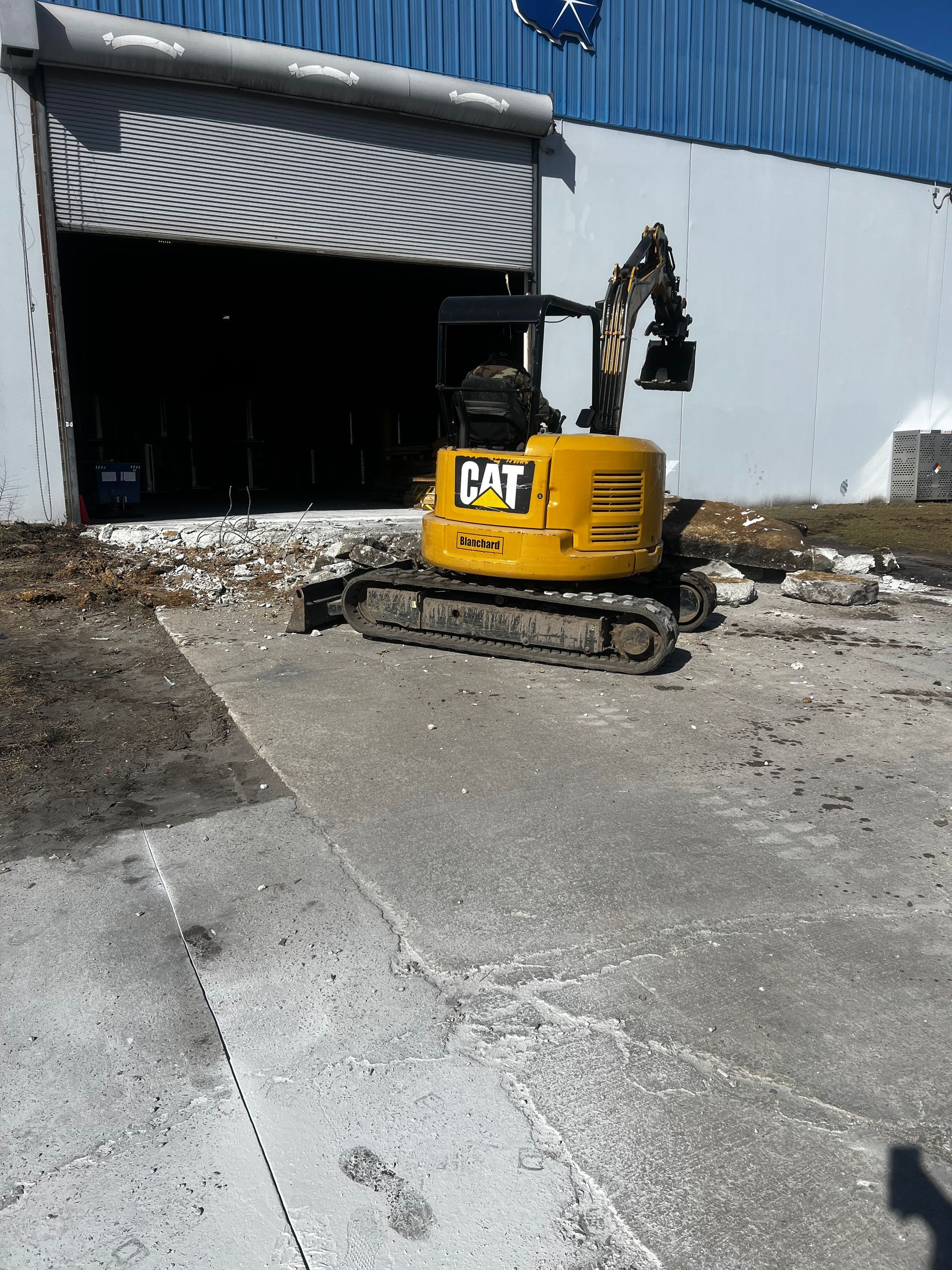 A yellow cat excavator is parked in front of a building