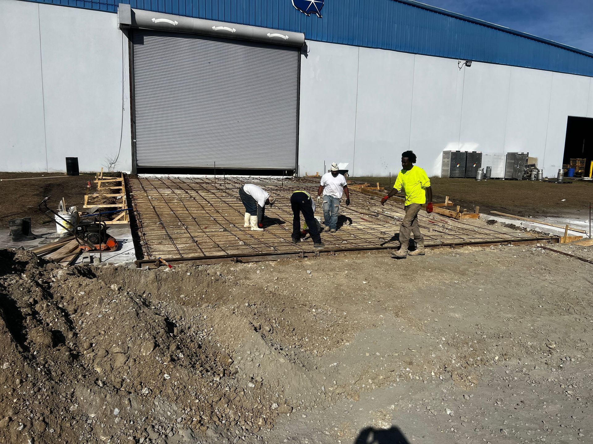 A group of construction workers are working on a ramp in front of a building.