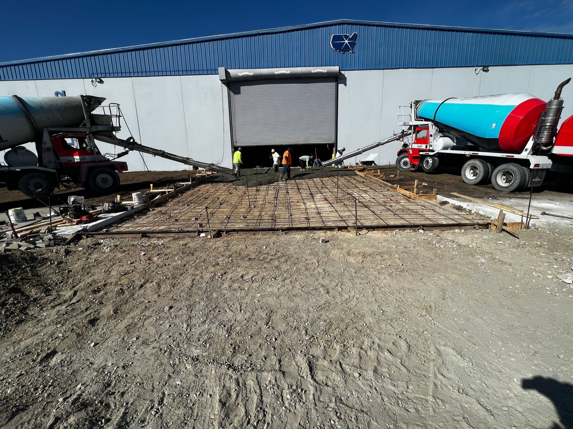 A concrete truck is pouring concrete in front of a building.